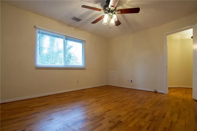 a view of an empty room with wooden floor and a window