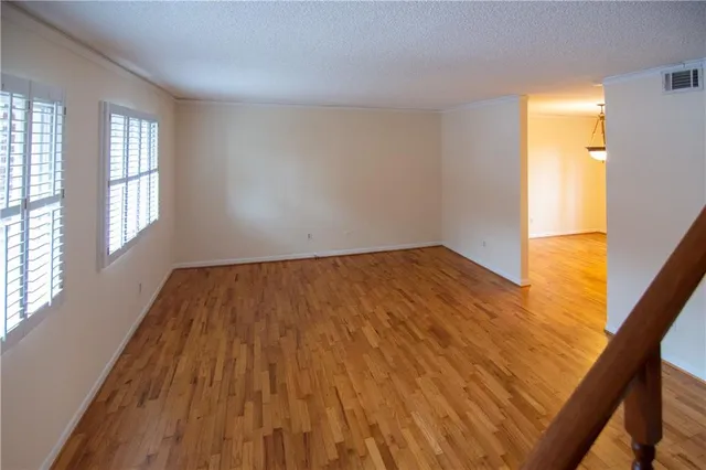 a view of empty room with wooden floor and fan
