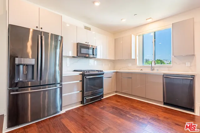 a kitchen with a refrigerator stove and wooden floor