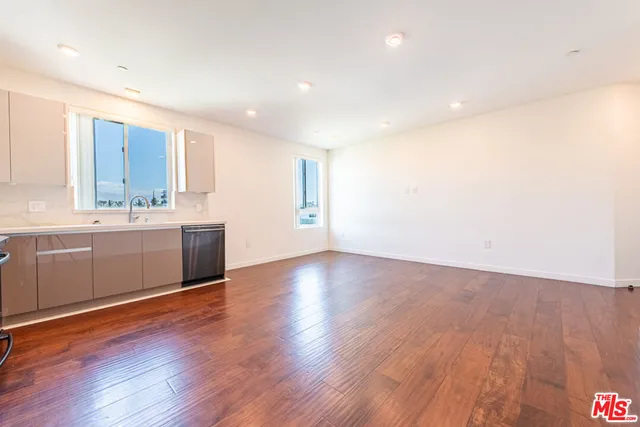 a view of a big room with wooden floor and windows