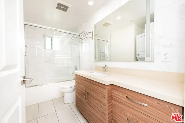a bathroom with a granite countertop sink a toilet a mirror and shower