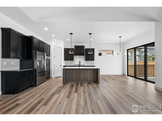 a kitchen with stainless steel appliances kitchen island granite countertop a refrigerator a sink dishwasher and wooden cabinets with wooden floor