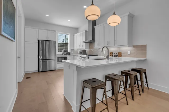 a kitchen with stainless steel appliances granite countertop a sink a stove a refrigerator cabinets and chairs