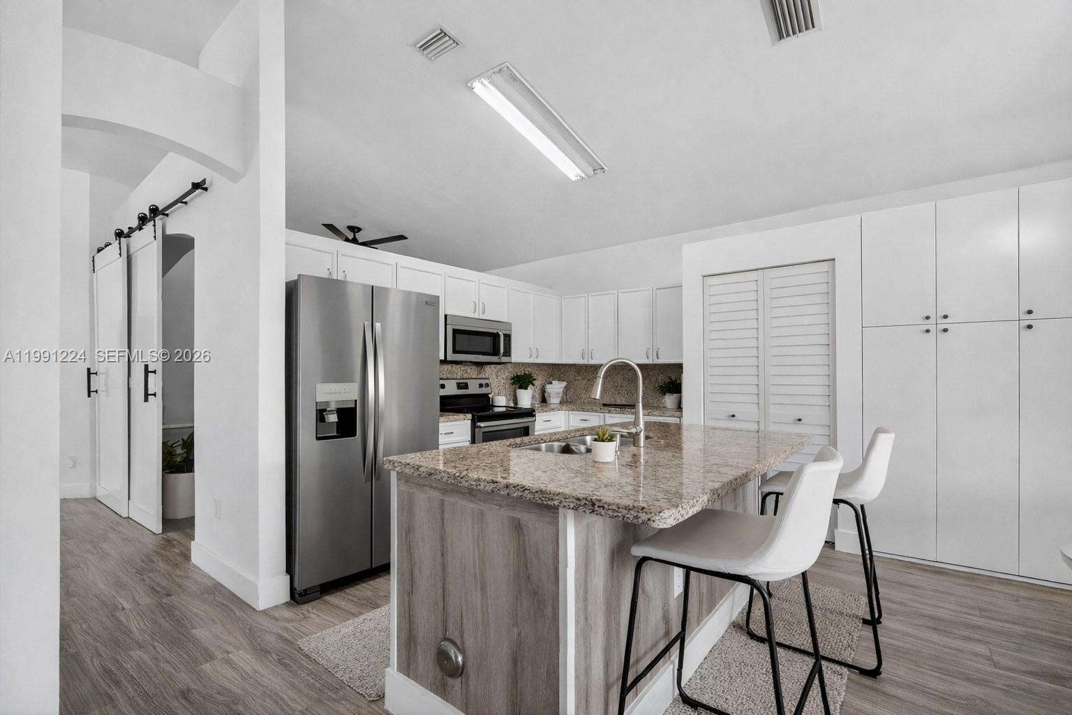 16299 Southwest 103rd Street Miami, FL 33196 - Photo 12 of 30 a kitchen with stainless steel appliances a refrigerator a stove a sink dishwasher with a dining table and chairs