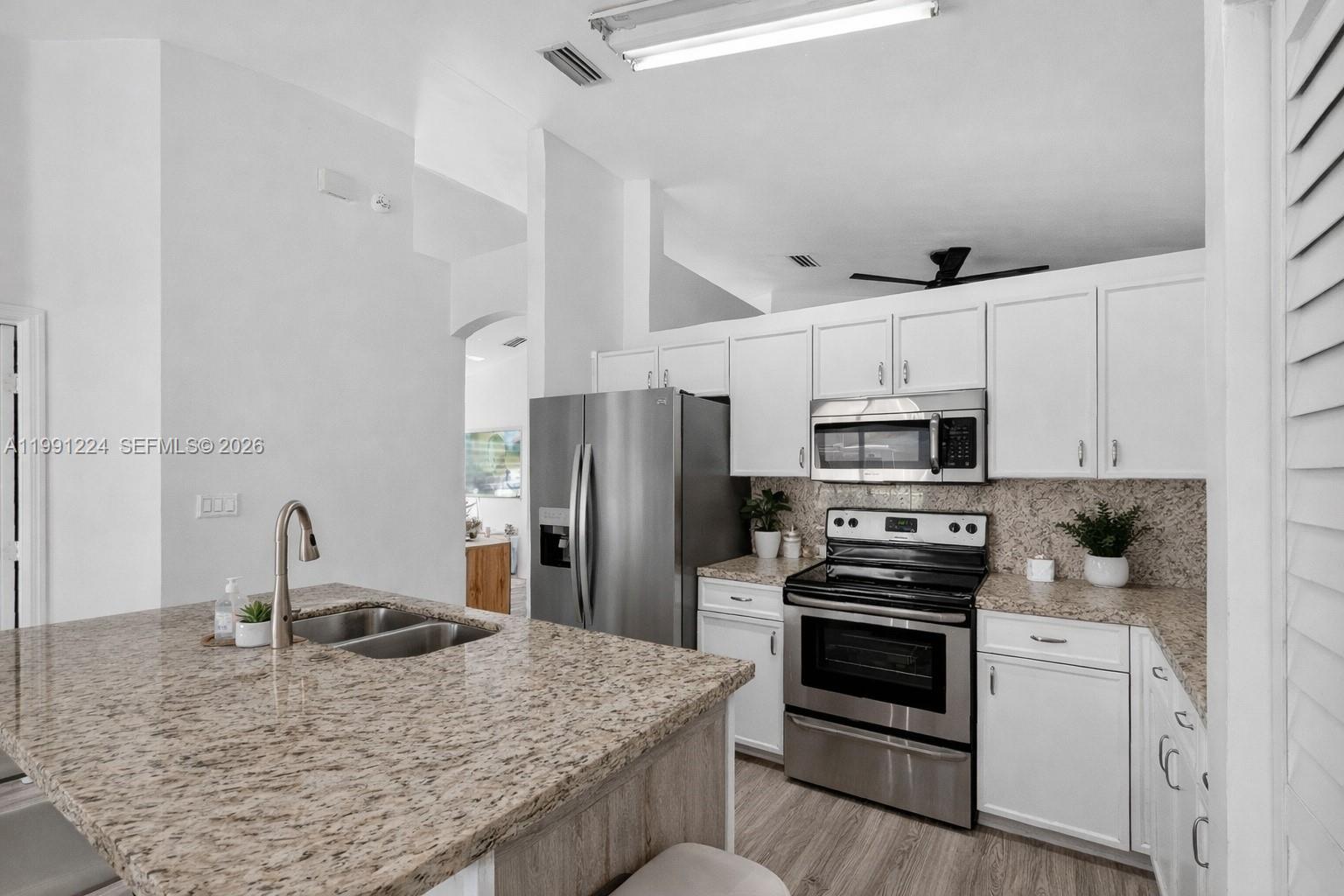 16299 Southwest 103rd Street Miami, FL 33196 - Photo 17 of 30 a kitchen with stainless steel appliances kitchen island granite countertop a stove sink and refrigerator