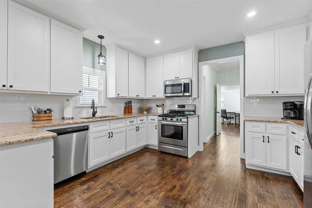 a kitchen with granite countertop white cabinets and stainless steel appliances