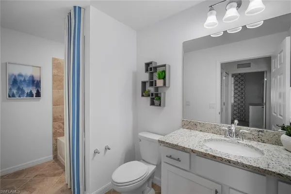 a bathroom with a granite countertop sink a toilet and a mirror