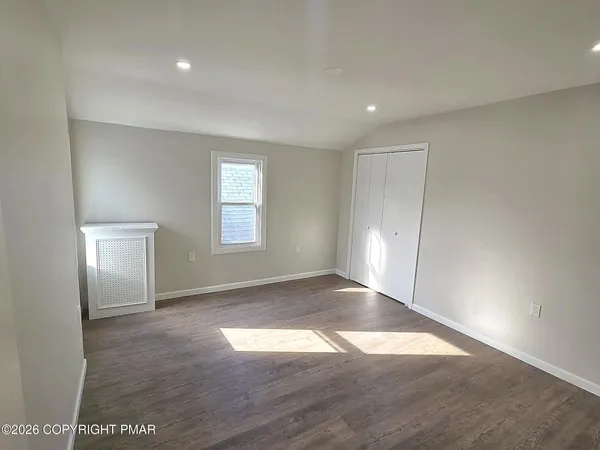 an empty room with wooden floor and windows