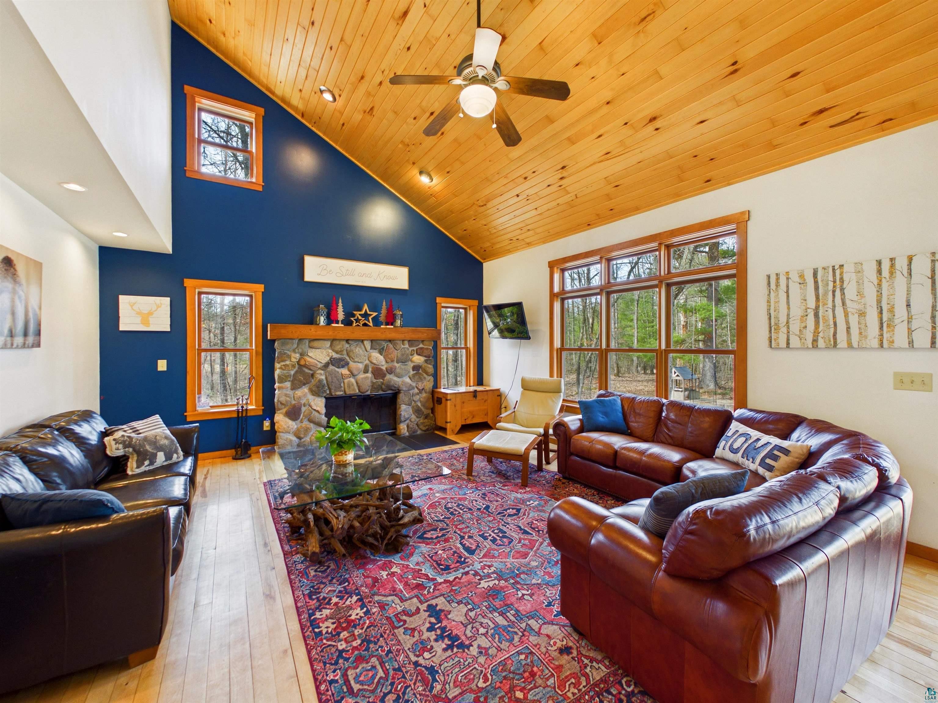 16539 Acorn Ridge Hayward, WI 54843 - Photo 18 of 58 Living room with light wood-style floors, a fireplace, a ceiling fan, and vaulted ceiling