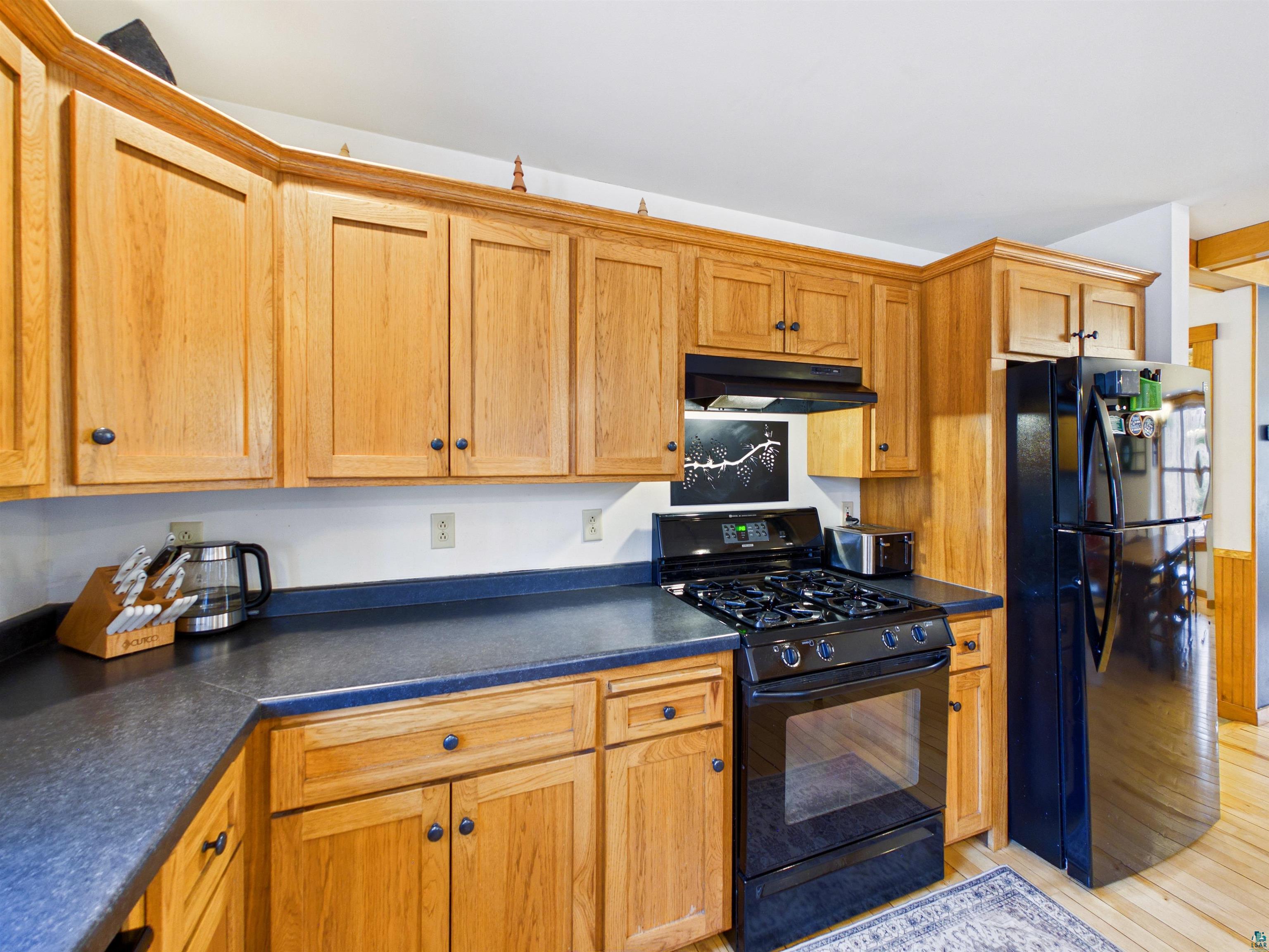 16539 Acorn Ridge Hayward, WI 54843 - Photo 24 of 58 Kitchen with black appliances, dark countertops, and light wood finished floors