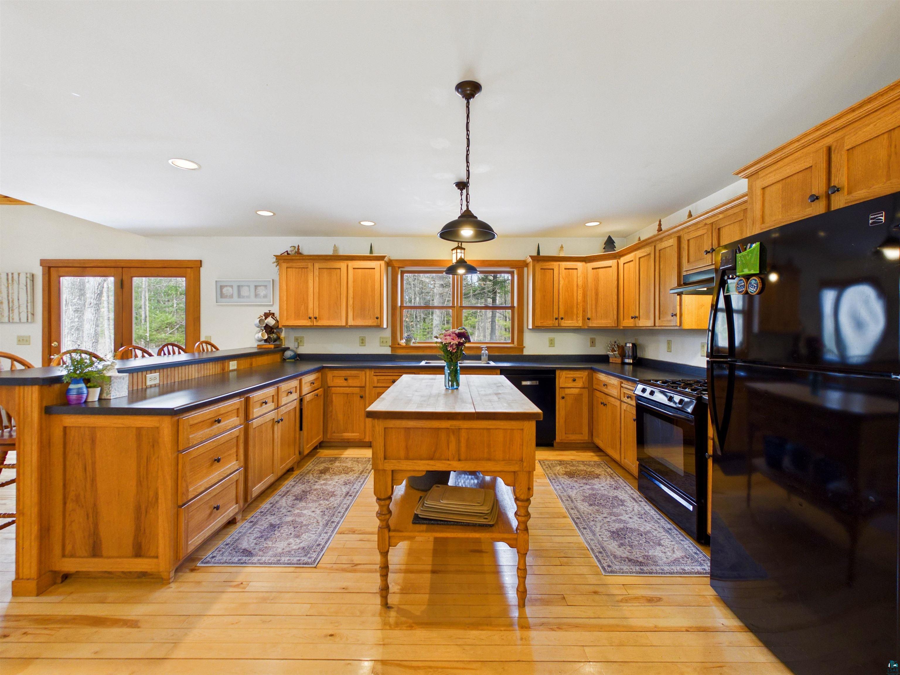 16539 Acorn Ridge Hayward, WI 54843 - Photo 25 of 58 Kitchen with a peninsula, black appliances, dark countertops, wood finish cabinets, and a breakfast bar area