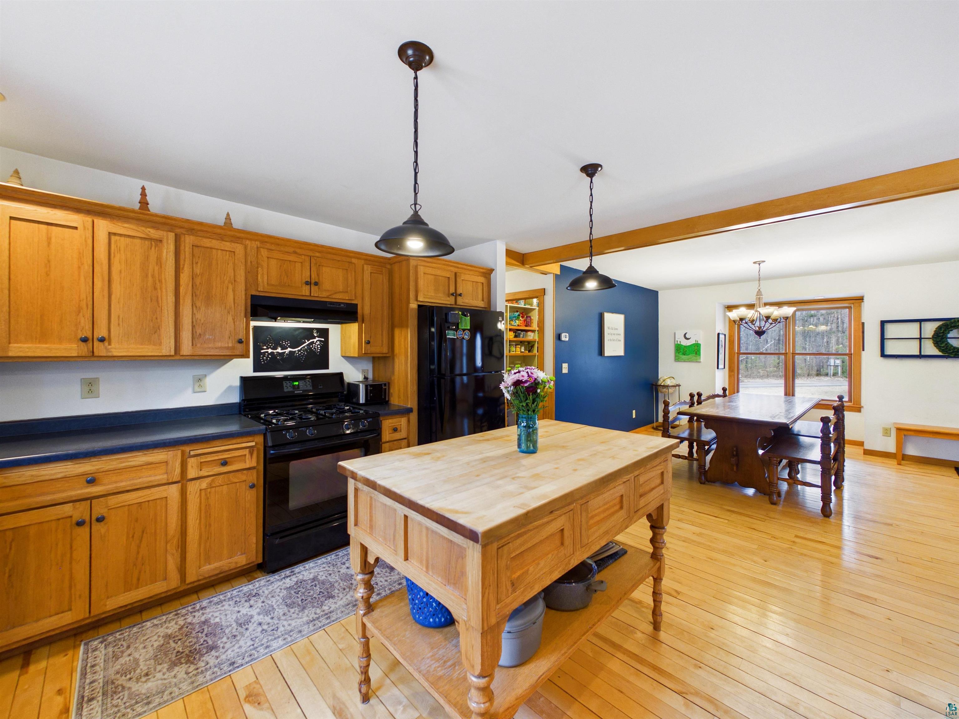 16539 Acorn Ridge Hayward, WI 54843 - Photo 26 of 58 Kitchen featuring dark countertops, black appliances, wood finish cabinets, light wood-style floors, and beam ceiling