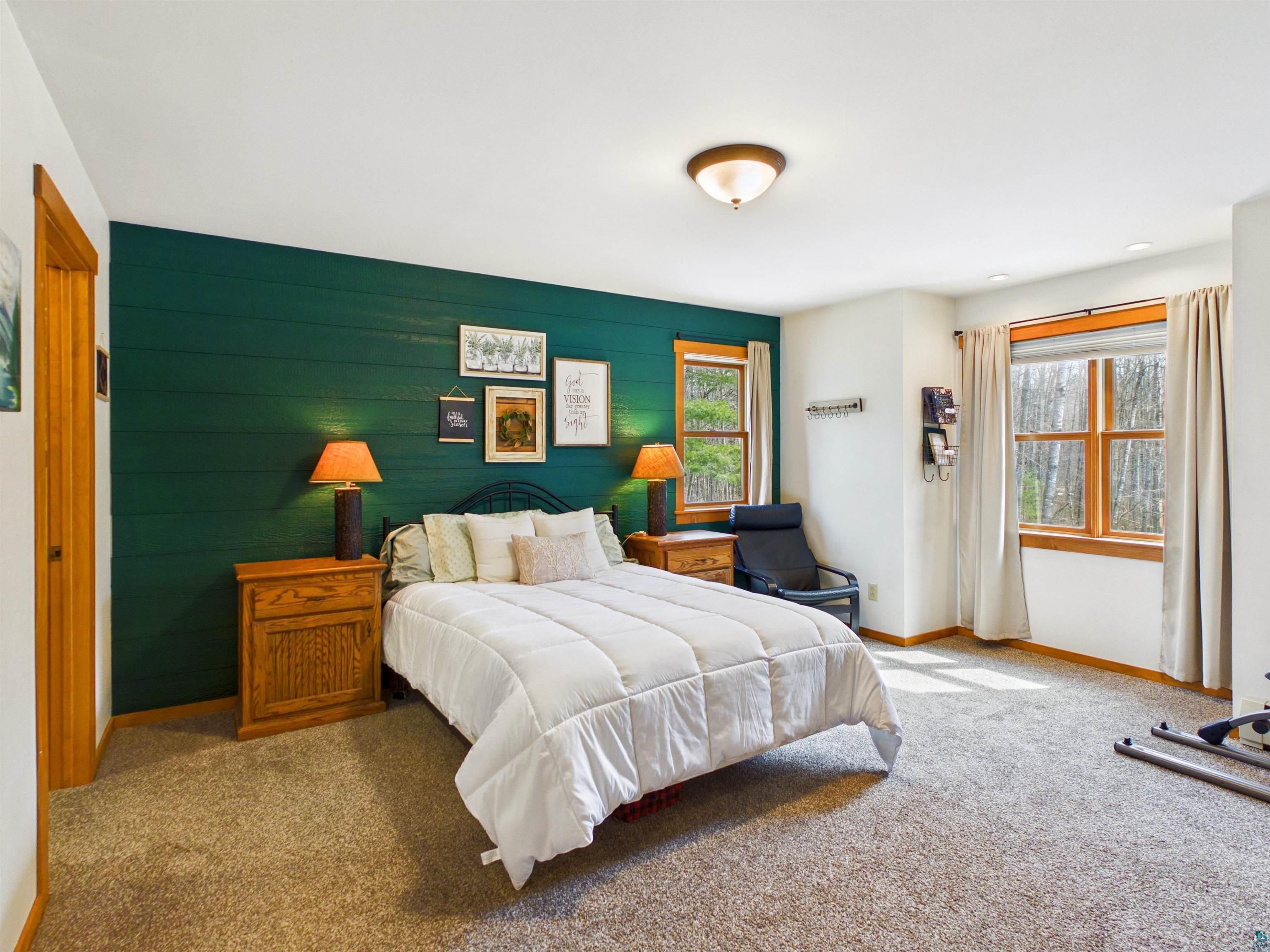 16539 Acorn Ridge Hayward, WI 54843 - Photo 34 of 58 Bedroom featuring multiple windows, wooden walls, carpet floors, and an accent wall