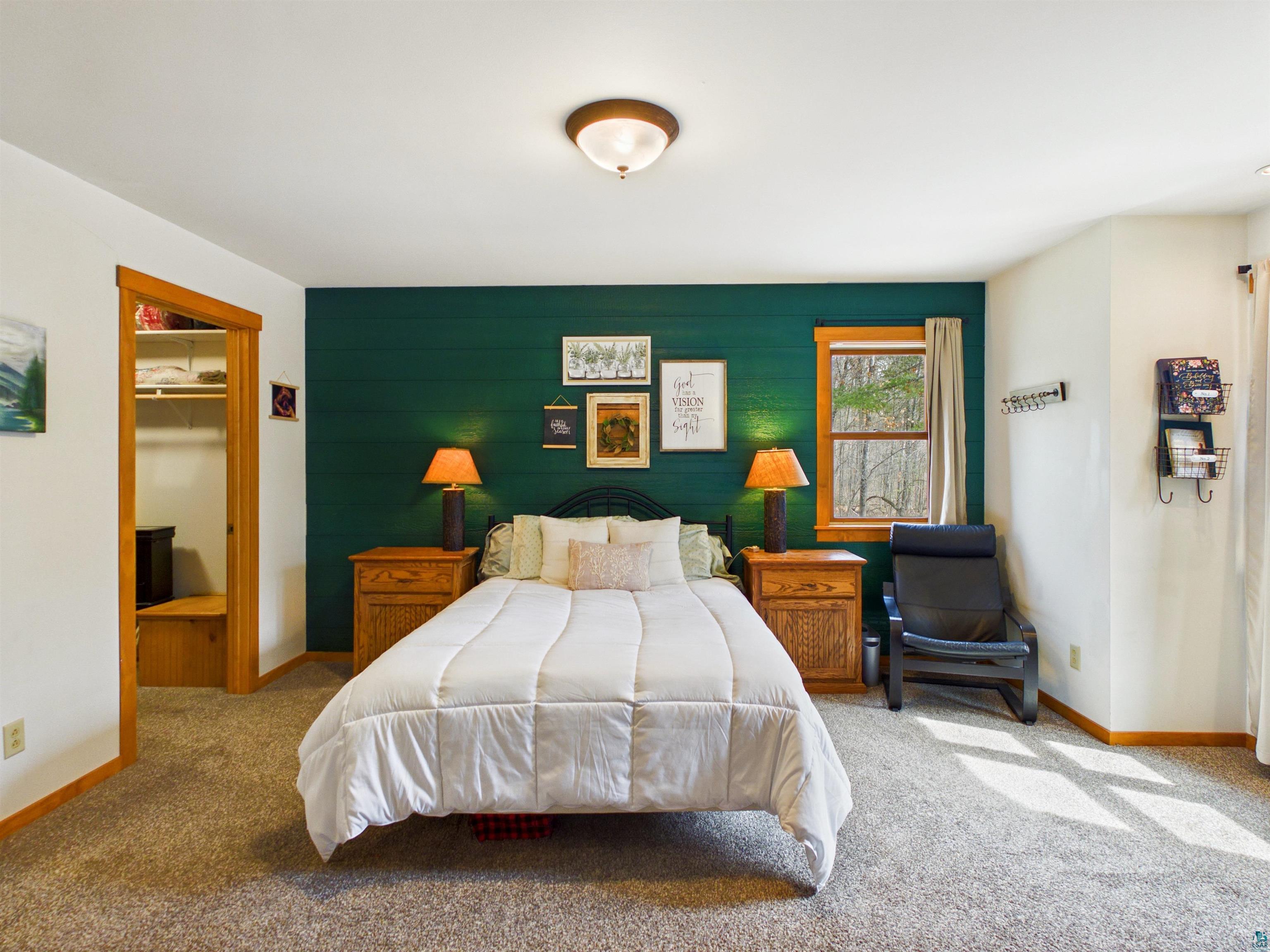 16539 Acorn Ridge Hayward, WI 54843 - Photo 35 of 58 Bedroom with a walk in closet, wooden walls, carpet flooring, and an accent wall