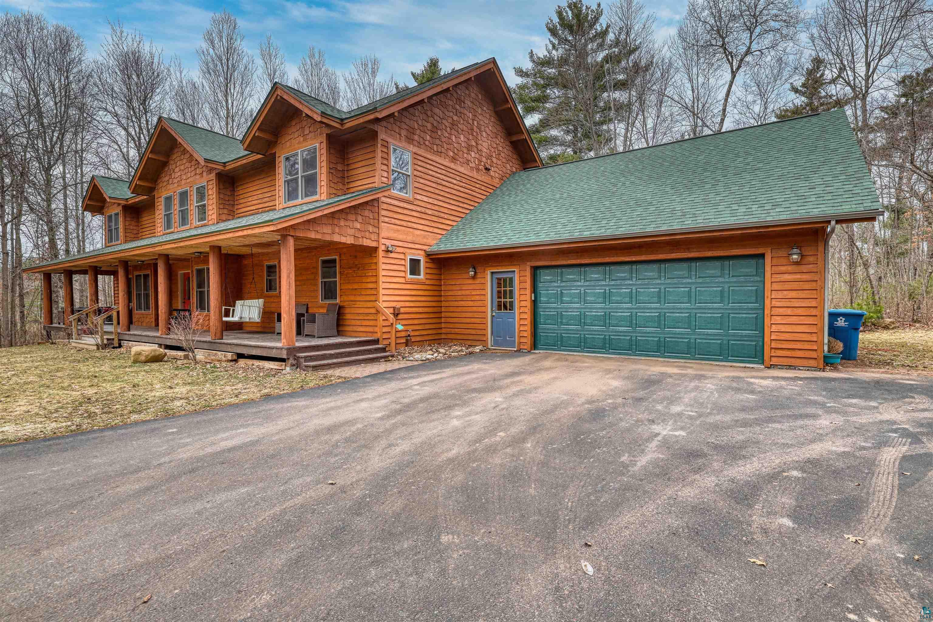 16539 Acorn Ridge Hayward, WI 54843 - Photo 5 of 58 Rustic home featuring asphalt driveway, a porch, roof with shingles, and an attached garage