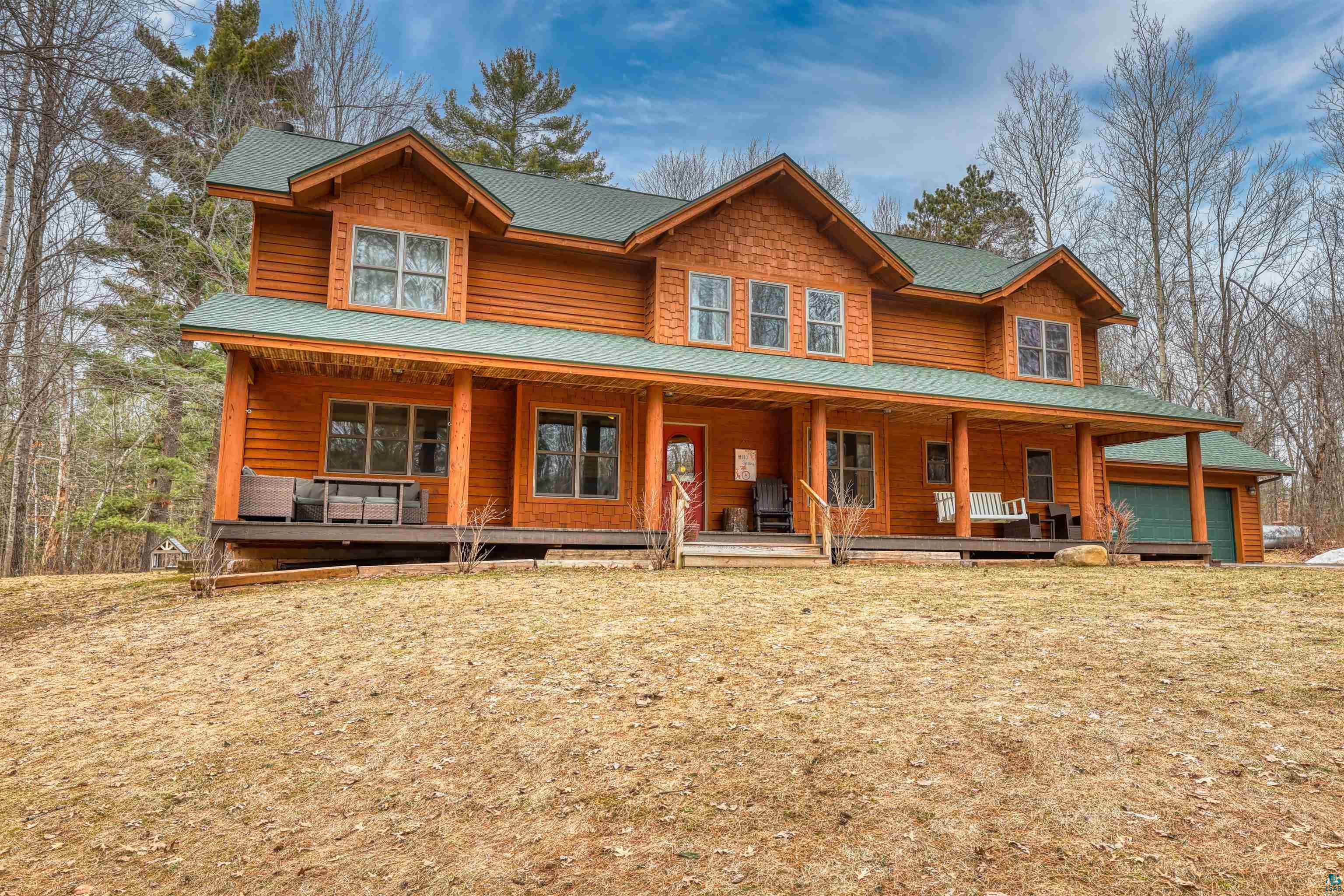 16539 Acorn Ridge Hayward, WI 54843 - Photo 51 of 58 View of front of house with a porch, a shingled roof, a front lawn, and a garage