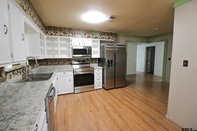 a kitchen with stainless steel appliances granite countertop a stove top oven a sink and a refrigerator
