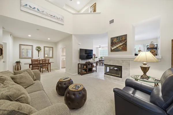 a living room with furniture a fireplace and floor to ceiling windows