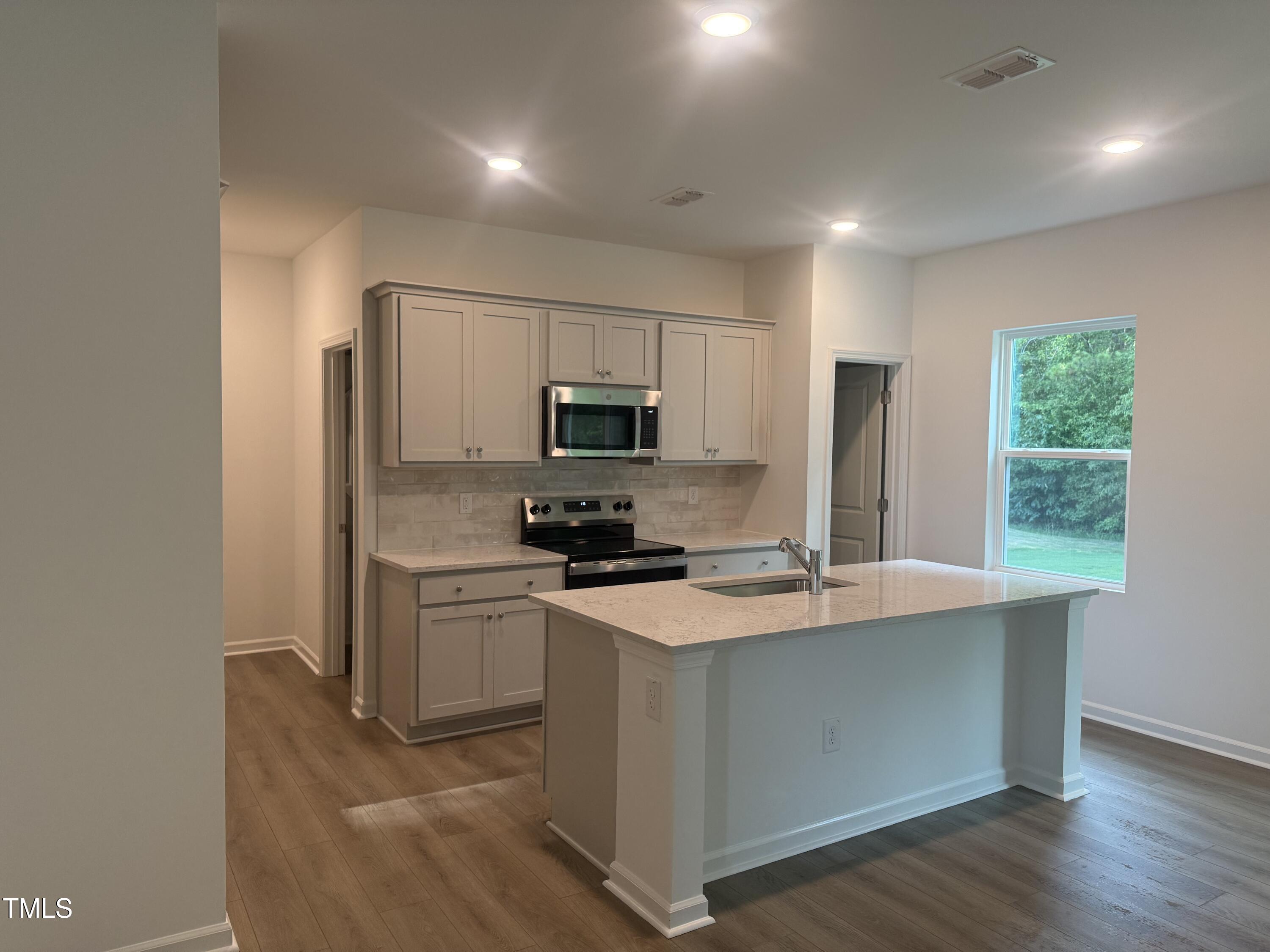 6828 Galloway Drive Middlesex, NC 27557 - Photo 2 of 32 a kitchen with a sink a stove a refrigerator a window and a kitchen island