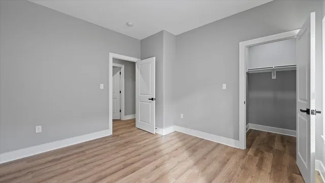 an empty room with wooden floor & closet area