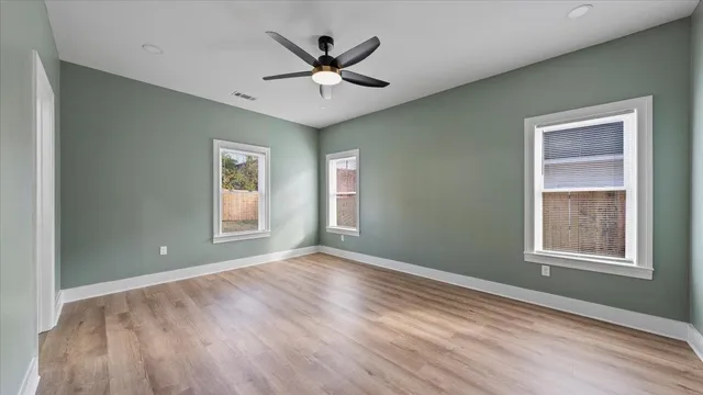 a view of an empty room with wooden floor and a window
