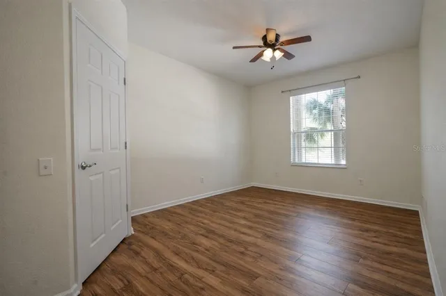 a view of a room with wooden floor and a ceiling fan