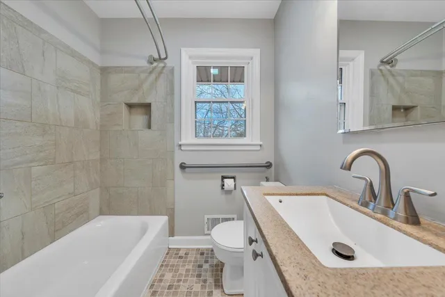 a bathroom with a granite countertop sink a toilet and bathtub
