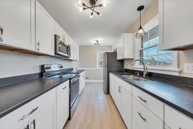 a large kitchen with stainless steel appliances granite countertop a sink a stove and a wooden floors