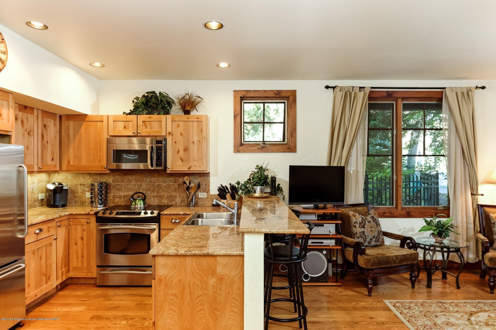 501 West Main Street, Unit A106 Aspen, CO 81611 - Photo 6 of 13 a kitchen with stainless steel appliances a stove top oven a sink a dining table and chairs