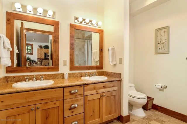 a bathroom with a granite countertop sink a toilet and a mirror