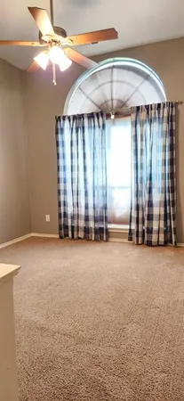 an empty room with windows and ceiling fan