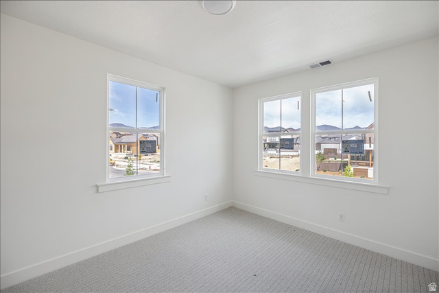 7189 South Sage Road, Unit 214 West Jordan, UT 84081 - Photo 21 of 29 Bright room featuring three windows with white trim, white walls, and patterned carpeting