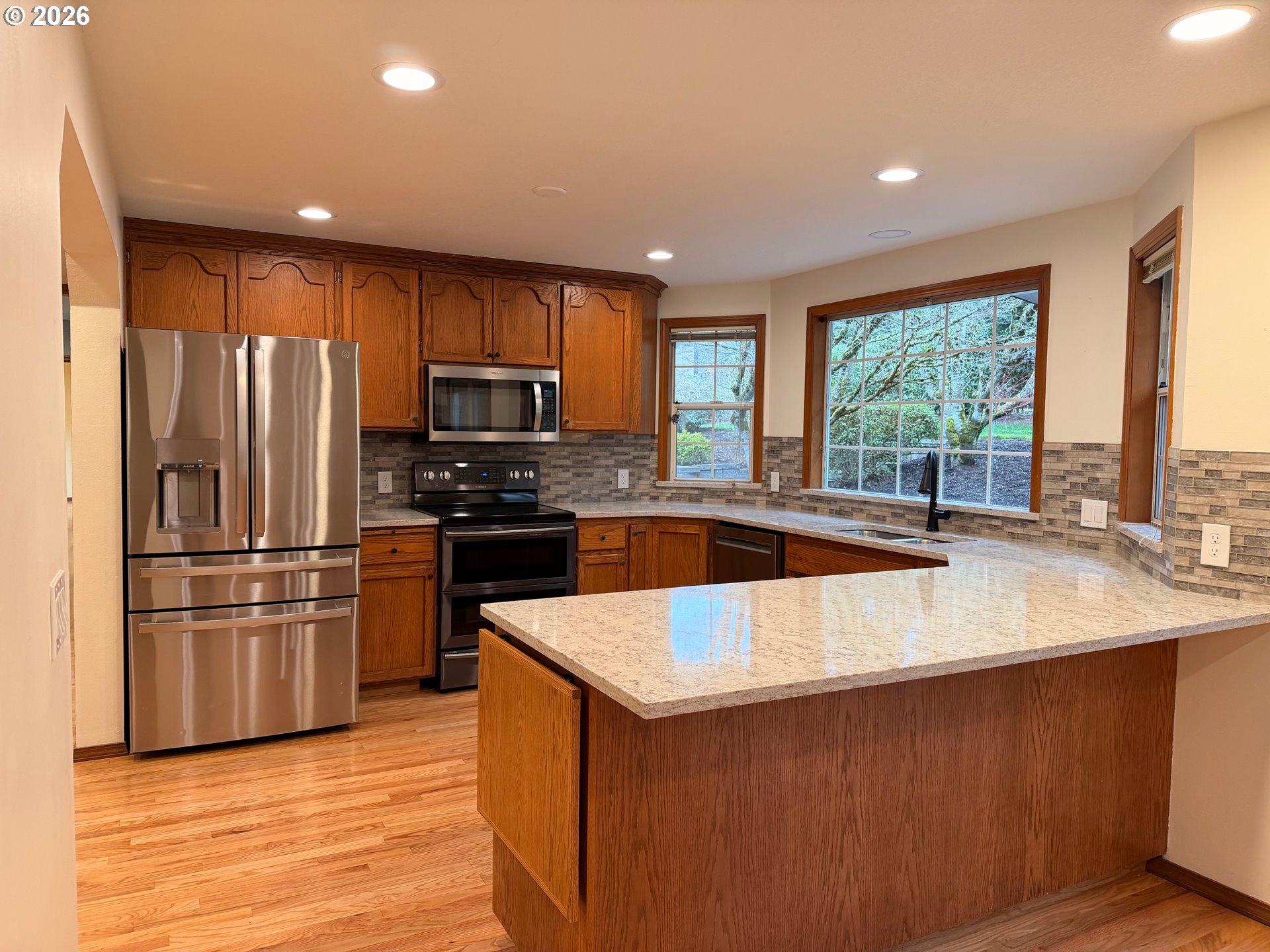 7505 Southwest Schroeder Way Wilsonville, OR 97070 - Photo 3 of 24 a kitchen with stainless steel appliances granite countertop a refrigerator a sink dishwasher a stove and a microwave oven with wooden floor