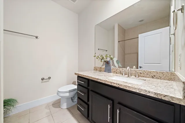 a bathroom with a granite countertop sink a toilet and a mirror