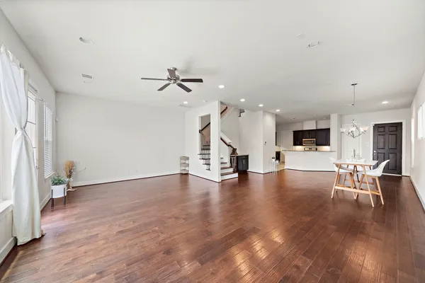 a view of an empty room with wooden floor and a ceiling fan