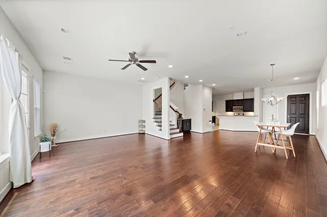 a view of an empty room with wooden floor and a ceiling fan