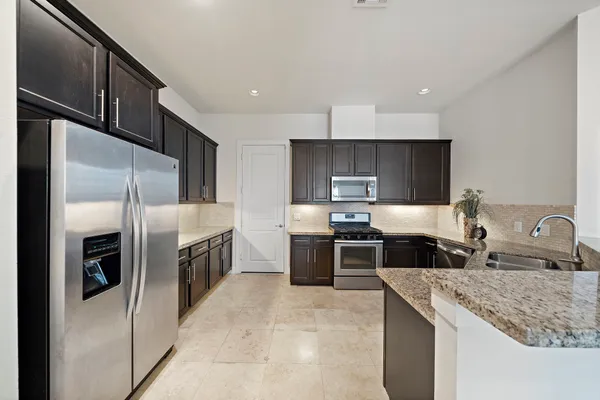 a kitchen with stainless steel appliances granite countertop a sink stove and refrigerator
