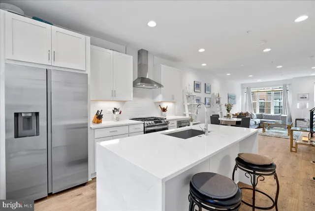 a kitchen that has a lot of white cabinets and stainless steel appliances
