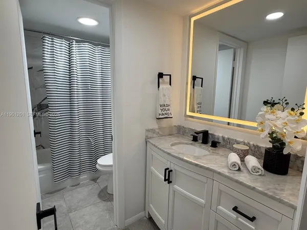 a bathroom with a granite countertop sink a toilet and mirror