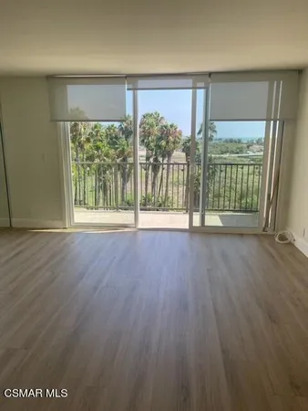 an empty room with wooden floor and balcony