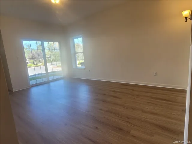 a view of an empty room with wooden floor and window