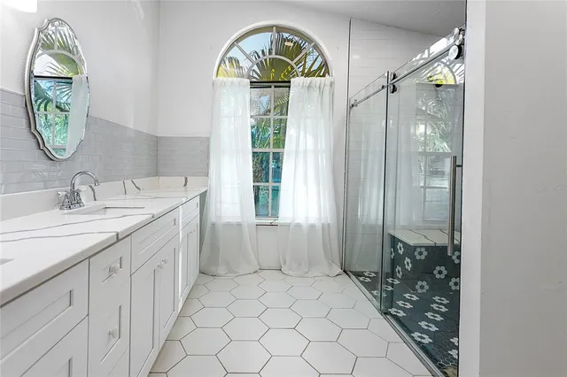 a bathroom with a granite countertop sink a mirror and a shower