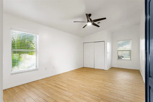 a view of empty room with wooden floor and fan