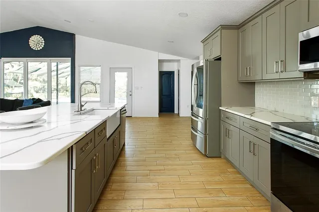 a large kitchen with stainless steel appliances granite countertop a sink and cabinets