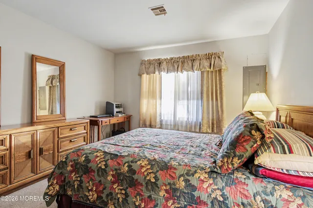 a bedroom with a bed and a large mirror on the dresser