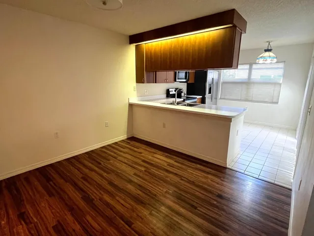 an empty room with wooden floor windows and a chandelier fan