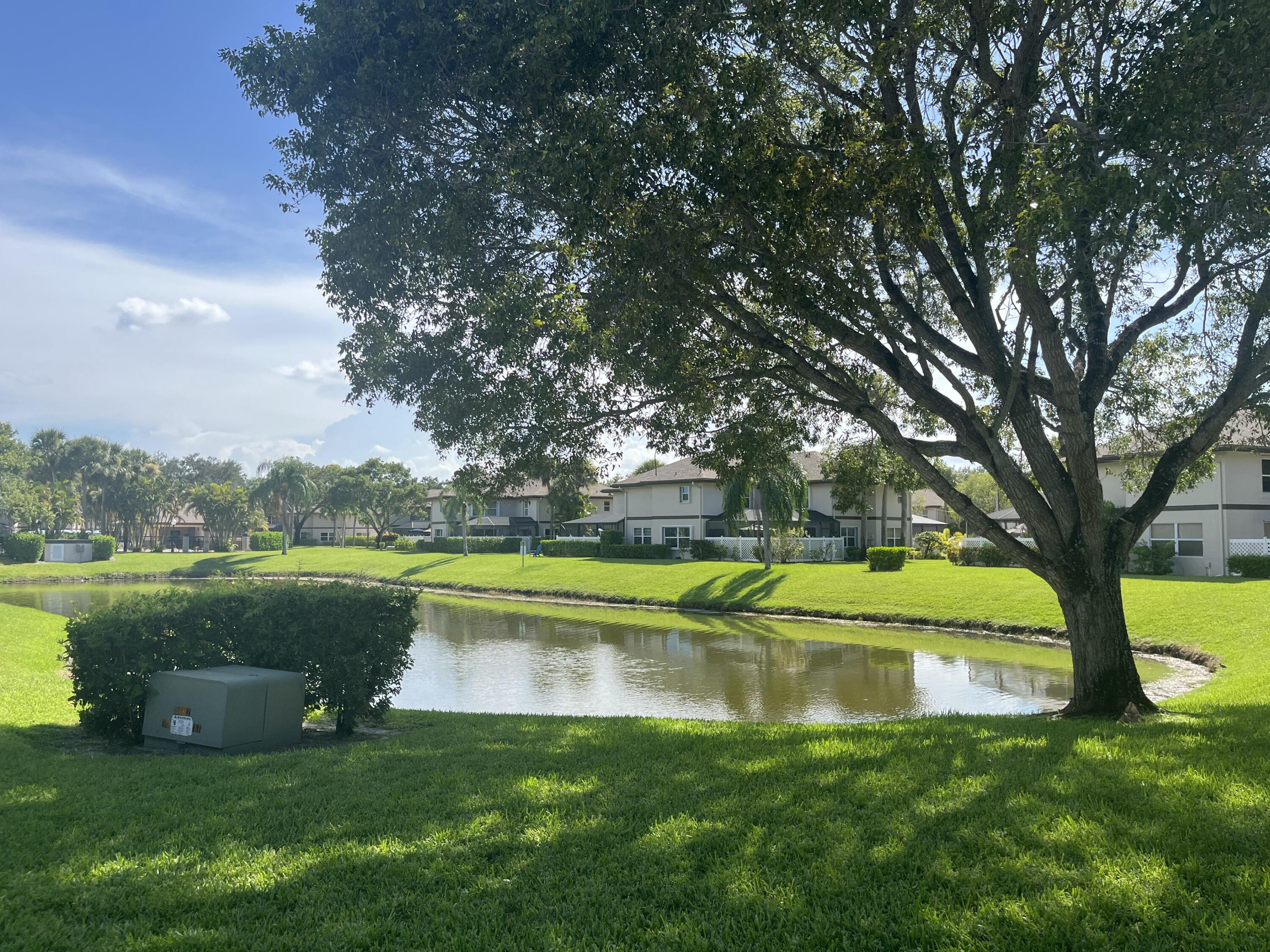 7 Amherst Court, Unit A Royal Palm Beach, FL 33411 - Photo 39 of 45 a view of a lake with a yard and large trees