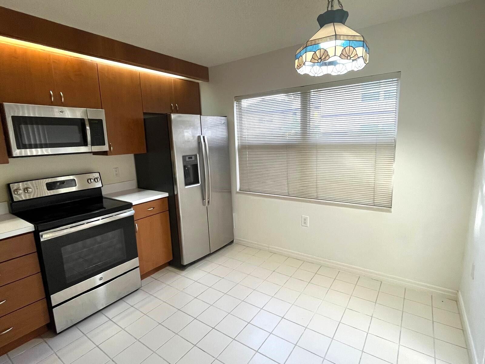 7 Amherst Court, Unit A Royal Palm Beach, FL 33411 - Photo 6 of 45 a kitchen with stainless steel appliances granite countertop a refrigerator and a stove top oven