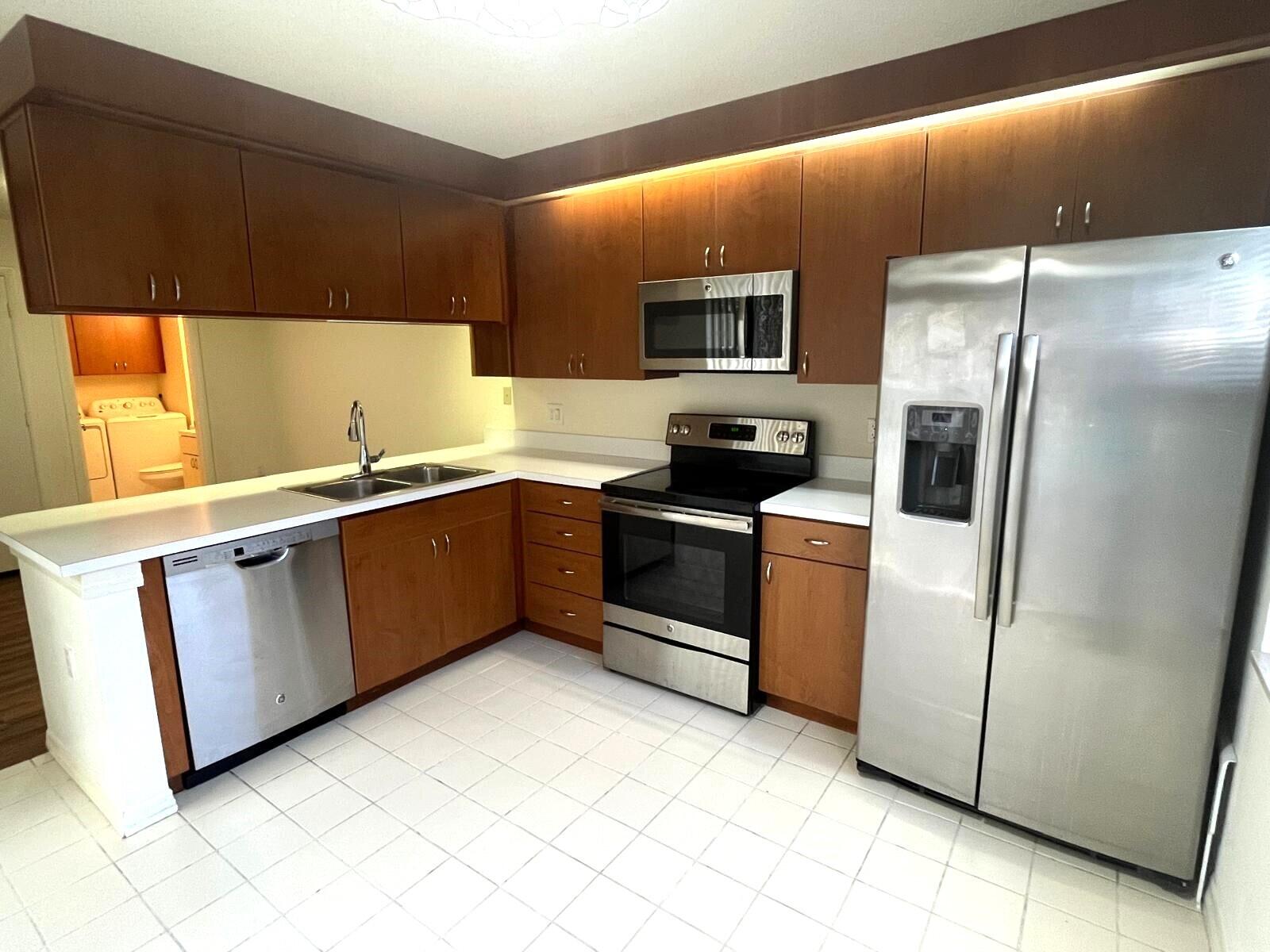 7 Amherst Court, Unit A Royal Palm Beach, FL 33411 - Photo 7 of 45 a kitchen with stainless steel appliances a sink a stove a microwave a refrigerator a counter top and cabinets