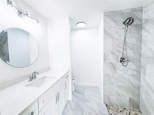 a bathroom with a granite countertop sink a mirror and shower